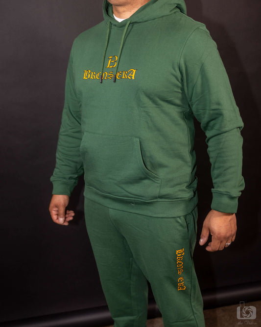 Model wearing a green Brons era hoodie made of organic cotton, featuring a relaxed fit and stylish logo design.